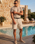 Man in beige knit t-shirt and shorts by the pool