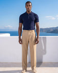 Man in navy half-zip knit polo with beige trousers, full summer look