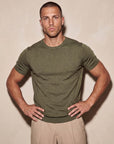 Man in olive green knit t-shirt with hand on hip, Morengar summer look