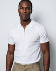 Man in white half-zip knit polo and beige trousers, menswear