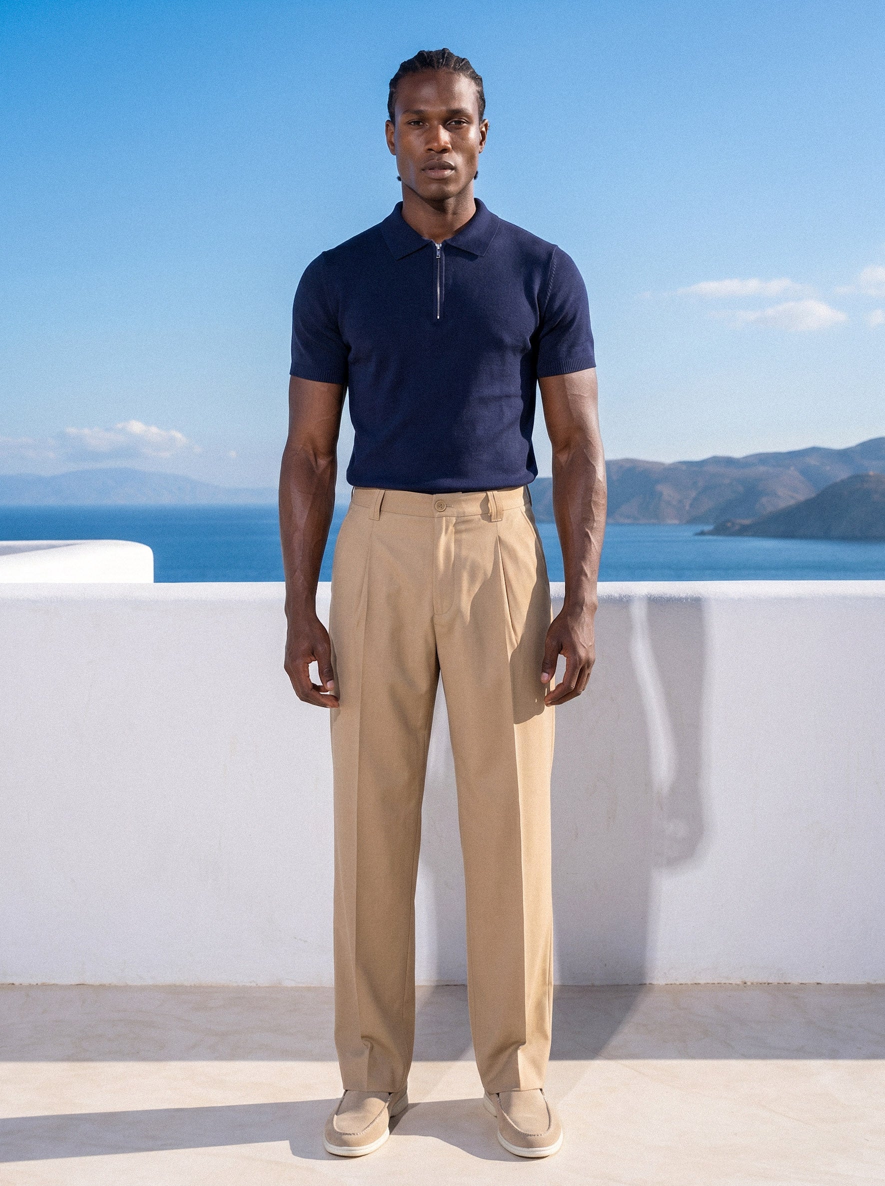 Man in navy half-zip knit polo with beige trousers, full summer look
