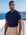 Man wearing navy knit polo by the sea, Morengar summer menswear