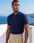 Man wearing navy knit polo by the sea, Morengar summer menswear