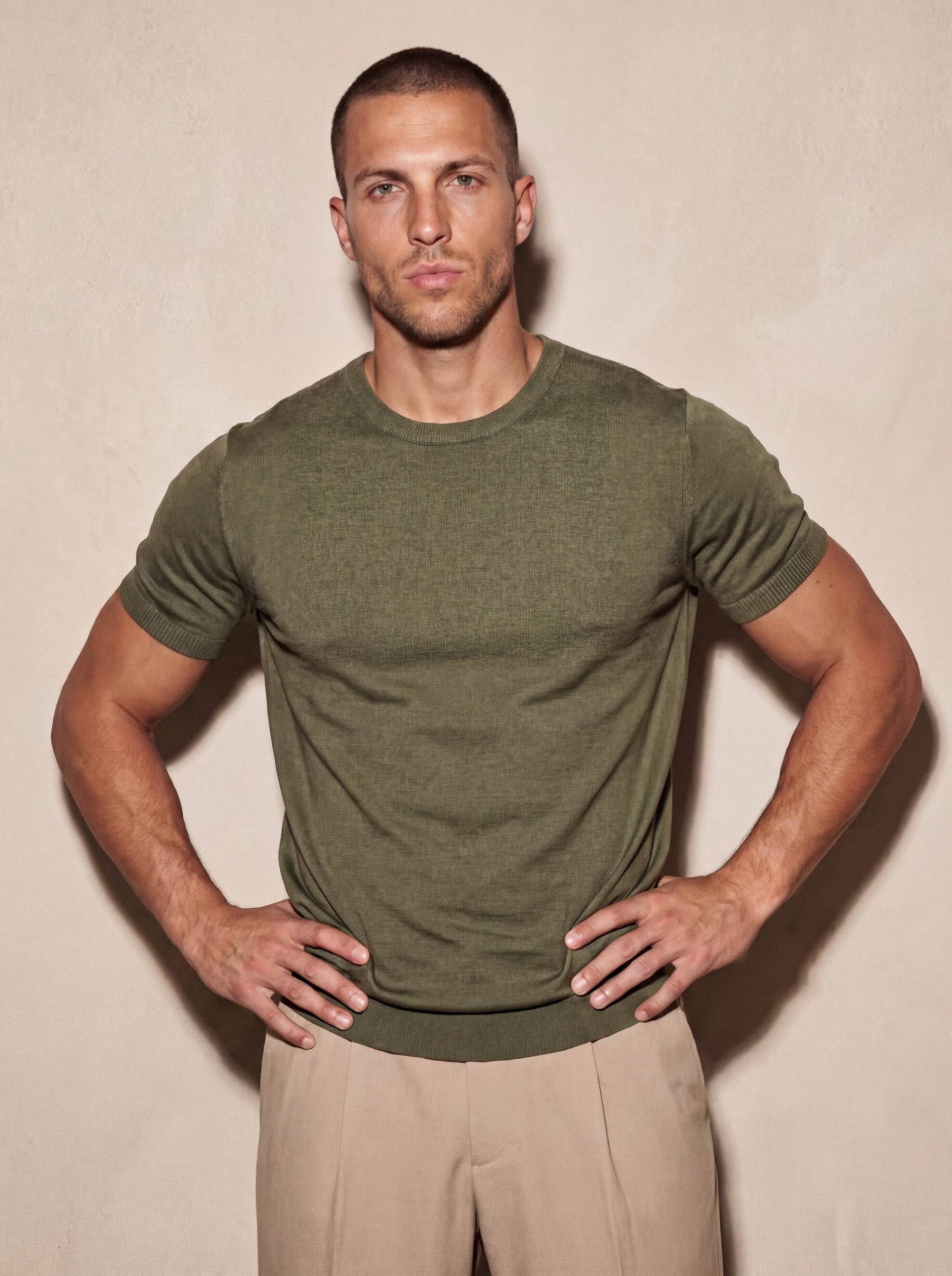 Man in olive green knit t-shirt with hand on hip, Morengar summer look