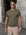 Man wearing olive green knit t-shirt by a stone wall, Morengar summer menswear