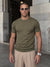 Man wearing olive green knit t-shirt by a stone wall, Morengar summer menswear